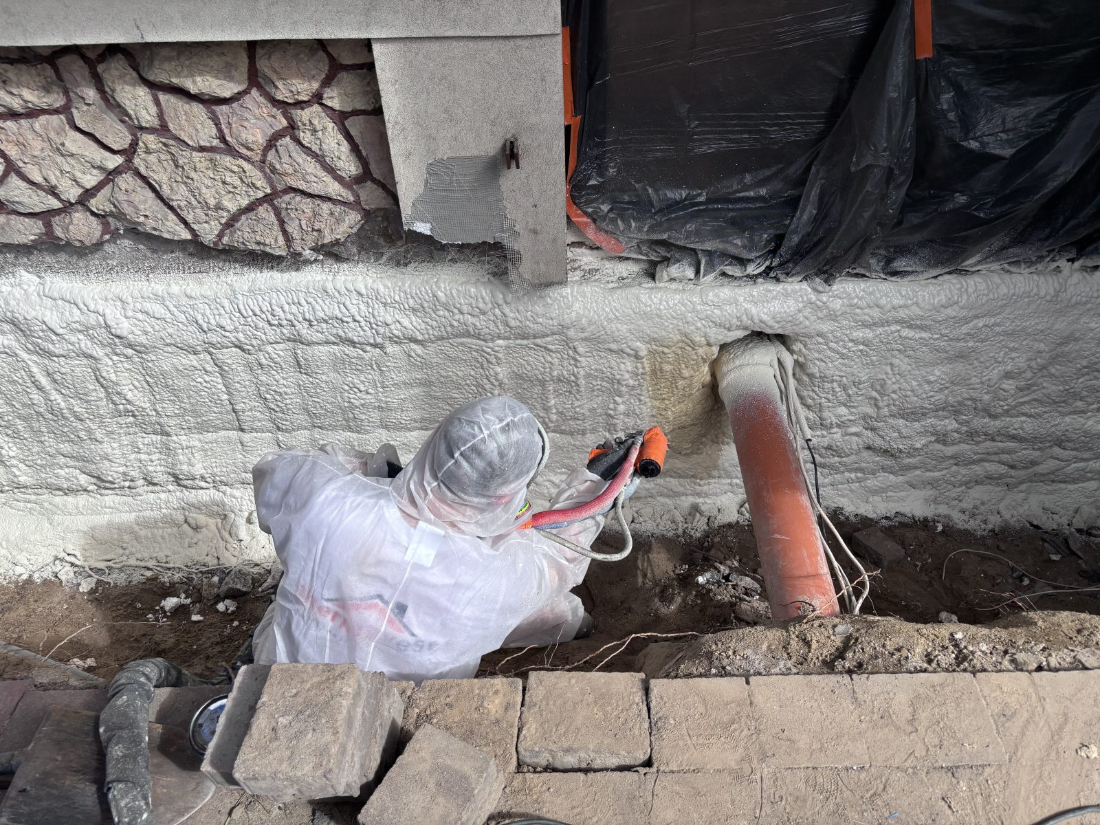 Ocieplenie fundamentów pianą PUR — aplikator Thermovest natryskuje pianę na odkopaną ścianę fundamentową