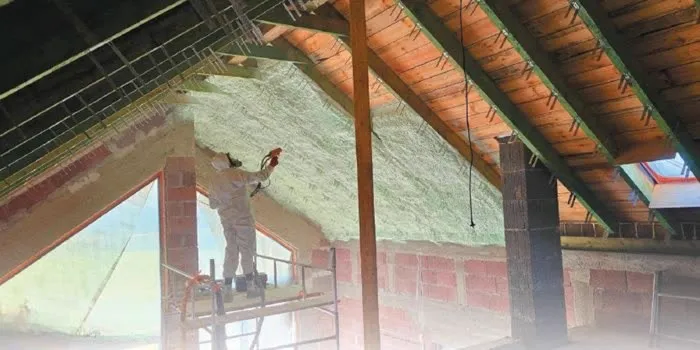 Wykonawca natryskujący piankę PUR na połać dachu poddasza